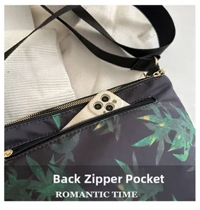 Detail of back zipper pocket on black tote bag with green leaf print and gold hardware