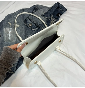 Détail du sac cabas blanc semi-verni avec boucles magnétiques dorées et capacité interne