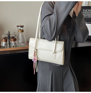 Chic cream faux leather shoulder bag styled on model in minimalist interior setting