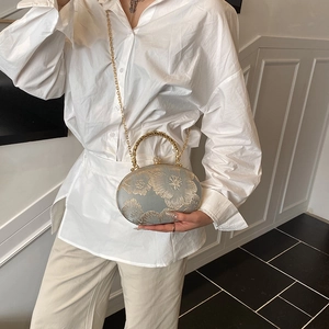 Elegant grey embroidered handbag with gold floral patterns and a round metal handle