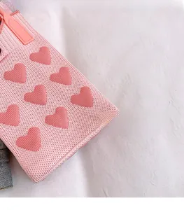 Detail of pink knitted bag featuring red heart patterns and high-quality jacquard texture