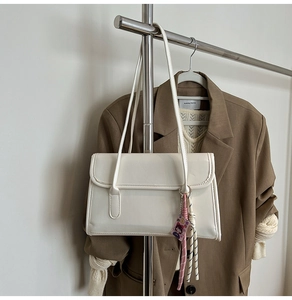 Détail du sac cabas blanc rectangulaire avec doubles bretelles et pendentif tressé