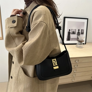Sac bandoulière noir minimaliste avec boucle grecque dorée et détail de bandoulière nouée