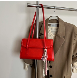 Détail du sac à bandoulière en cuir rouge avec fines lanières et breloques décoratives
