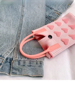 Detailed view of pink knitted mini bag with textured heart patterns and snap button