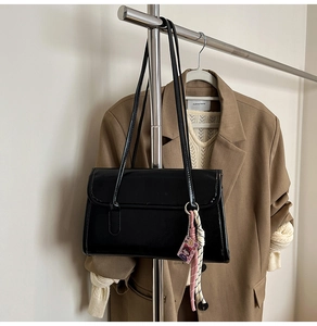 Détail d'un sac cabas noir brillant minimaliste avec pendentif tressé décoratif