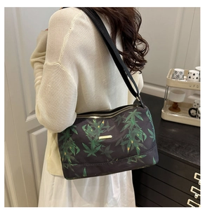 Detail of floral tote bag with green leaf prints, golden logo and double zipper closure