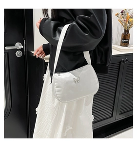 Detail of white half-moon underarm bag with silver butterfly buckle on wide shoulder strap