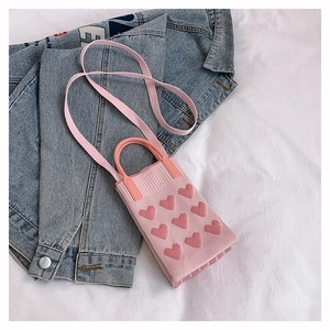 Détail du mini sac tricoté rose avec motifs de cœur en 3D sur une veste en jean