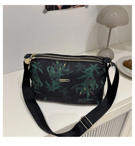 Detail of three-layer gold heart zippers and maple leaf print on black crossbody bag