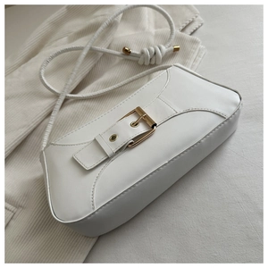 Detail of white leather shoulder bag featuring decorative gold buckle and knot strap detail