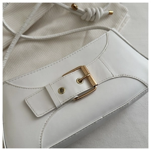 Detailed macro view of white minimalist underarm bag with gold metal buckle and strap knot