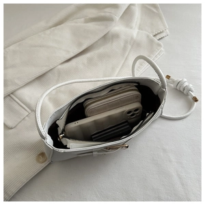 Internal storage of a white leather shoulder bag holding a wallet and smartphone