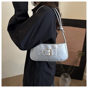Chic silver underarm bag with gold metal buckle shown on model in a minimalist room