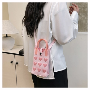 Knitted pink heart crossbody bag with 3D embroidery shown on a model in a stylish interior