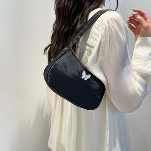 Black shoulder bag with a white butterfly buckle shown on a model for a minimal casual look