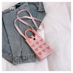 Détail de la pochette téléphone en tricot rose avec motifs cœurs 3D et anses rondes