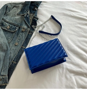 Gros plan du sac matelassé bleu roi avec chaîne argentée sur fond en jean bleu