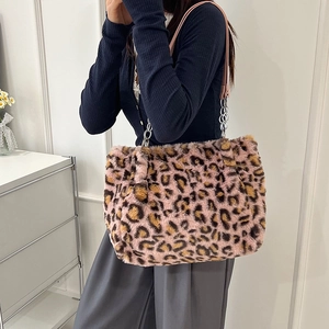 Pink leopard print faux fur tote bag with metal chain strap worn by a model