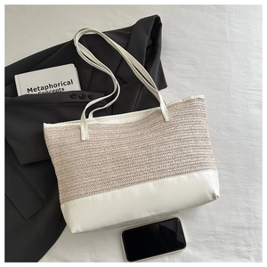 Detailed view of woven tote bag with white leather trim and sturdy shoulder straps