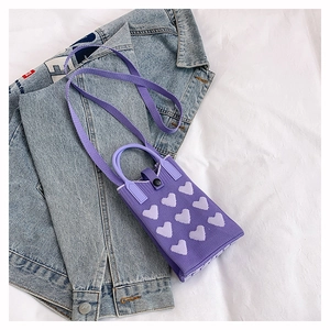 Détail du mini sac de téléphone en tricot violet avec motif de cœur et bandoulière tressée