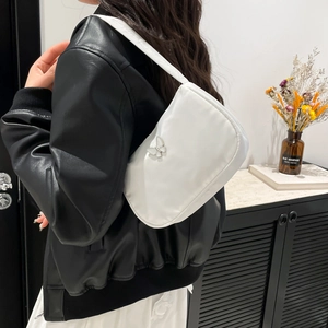 White underarm shoulder bag with silver butterfly detail and wide strap on model