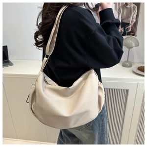 Modern cream crescent shoulder bag with wide adjustable strap on a model back view