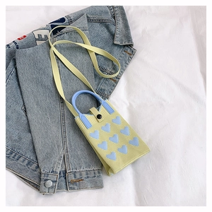 Détail du mini sac tricoté jaune avec cœurs bleus et fermeture à bouton pression
