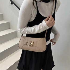 Chic beige underarm bag with gold buckle strap detail, styled in a minimalist studio setting