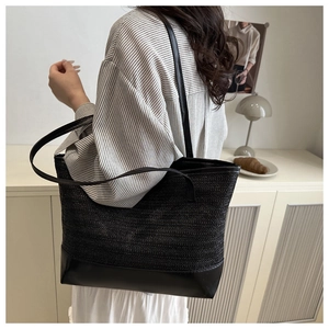 Detail of handwoven black tote bag with premium leather straps and textured pattern