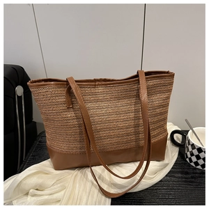 Detail view of large woven straw tote bag with brown synthetic leather base and straps