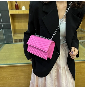 Sac matelassé rouge rose avec chaîne argentée porté avec une veste de blazer noire