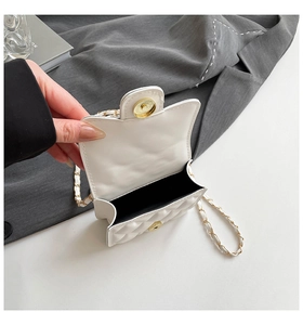 Detail of white quilted crossbody bag with golden magnetic clasp and chain strap