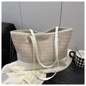 Close-up of woven straw tote bag with white faux leather trim and high-texture detail