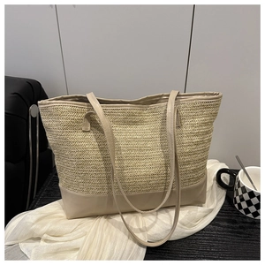 Close-up of the woven V-pattern texture and long faux leather handles on a beige tote bag