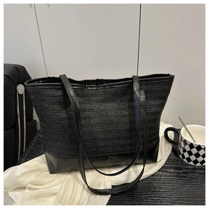 Detailed macro view of V-shaped woven texture and smooth leather trim on a black tote bag