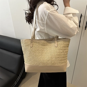 Chic woven tote bag with brown leather handles worn by a model in a minimalist home setting