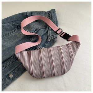 Detail of striped canvas chest bag with pink adjustable strap on denim jacket background