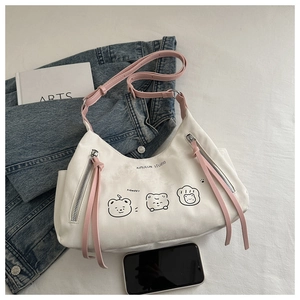 Detailed view of canvas tote bag featuring bear print, pink tassels and zipper closure