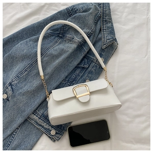 Close-up of white leather baguette bag with gold horseshoe buckle and chain detail