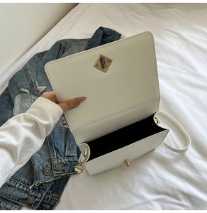 Detail of white PU leather crossbody bag with gold twist lock and black fabric lining