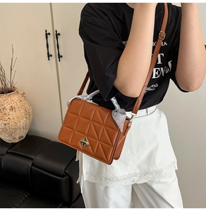 Brown quilted crossbody bag with golden twist lock and decorative silk scarf handle