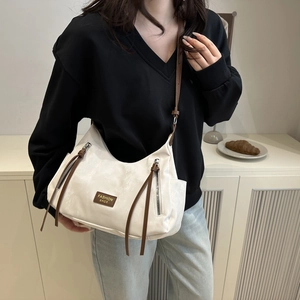 White crescent hobo bag with brown tassels and shoulder strap shown in a lifestyle setting