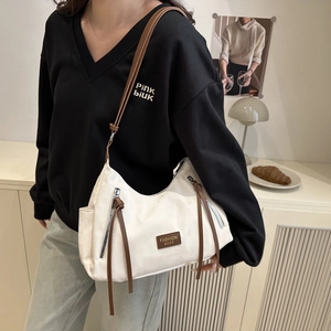 Minimalist beige faux leather tote bag with brown straps worn cross-body by a model
