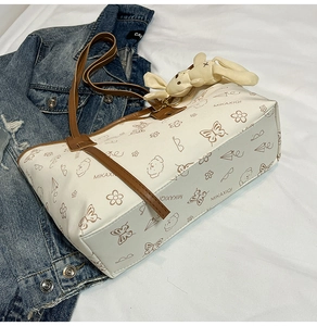 Gros plan du sac fourre-tout blanc avec motifs de dessins animés et breloque lapin en peluche