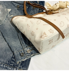 Détail du cabas en cuir blanc avec motifs de dessins animés et pendentif lapin en peluche