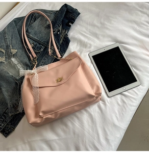 Dettaglio della borsa tote in pelle rosa con chiusura a scatto dorata e fiocco in pizzo