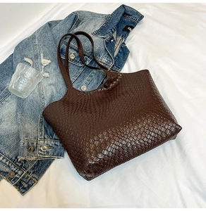 Detail view of dark brown woven leather tote bag with classic intrecciato texture pattern