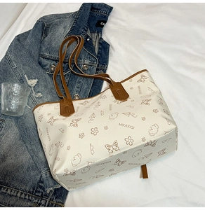 Top-down view of a spacious white tote bag with brown straps and floral line art prints
