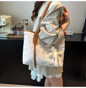 Détail du grand sac cabas blanc avec motifs graffiti et un pendentif lapin en peluche